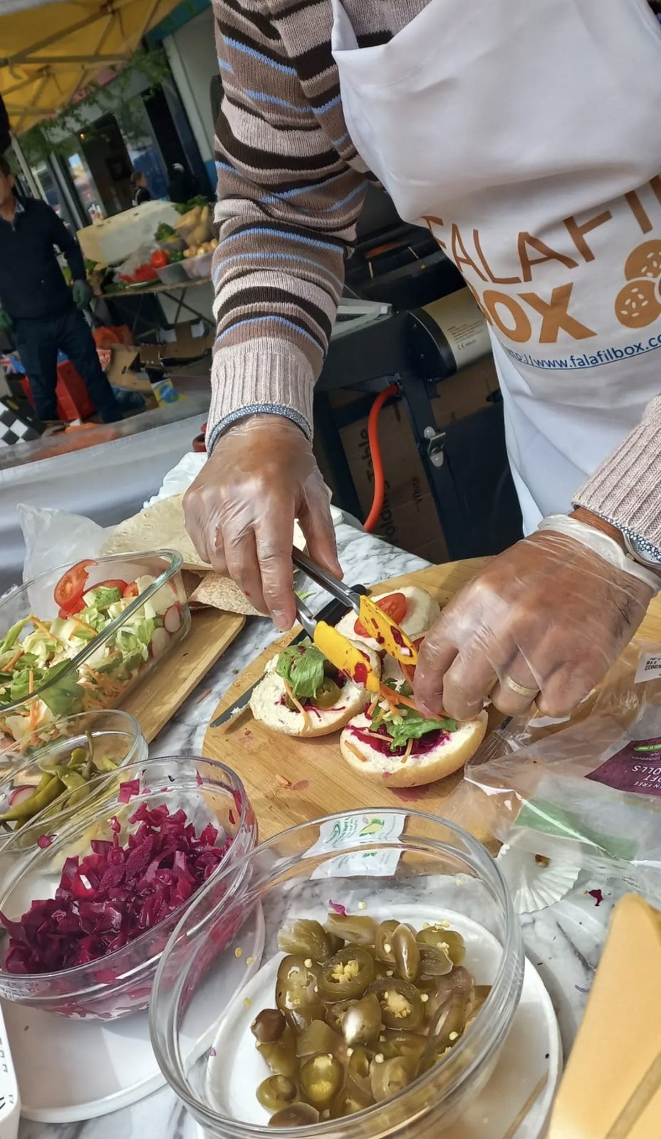 Falafel wrap being assembled at the stall with fresh vegetables
